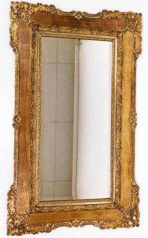 An Edwardian gilt framed wall mirror, with central rectangular mirror plate, and carved floral borders with scroll detailing, 140cm high, 83cm wide.