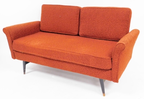 A retro 1960s Rest-u-Well two seater low sofa, with orange floral upholstery on mahogany capped legs, 83cm high, 142cm wide, 63cm deep. The upholstery in this lot does not comply with the 1988 (Fire & Fire Furnishing) Regulations, unless sold to a known e