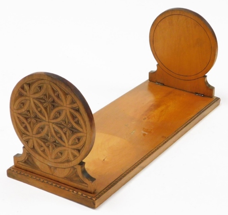 A late 19thC walnut bookstand, with flap circular carved ends, and panelled borders, 49cm wide, 18cm deep.