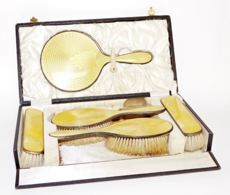 A silver and yellow enamelled dressing table set, with hand brushes, mirror and side brushes, in a fitted case, Birmingham.