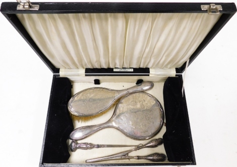 A George VI silver cased dressing table set, comprising hand brush, hand mirror, and glove stretchers, the mirror and brush each with floral scrolled detailing and decoration of bows, Birmingham 1946, with a matched pair of glove stretchers, with floral e