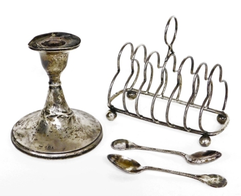 A group of silverware, to include an Edward VII silver six shelf toast rack, Birmingham 1907, on bun feet (AF), 4¼oz, together with two silver teaspoons, ¾oz, and a weighted silver dwarf candlestick (AF). (4)