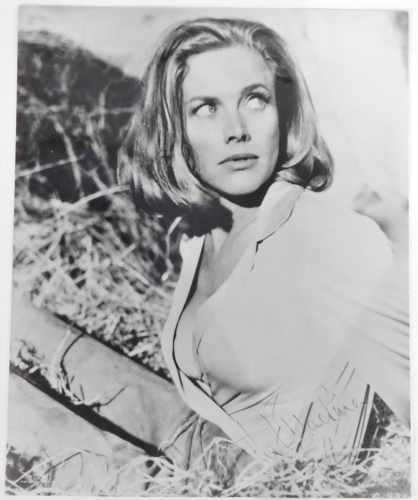 Honor Blackman. A signed black and white photograph of the actress in the stables at Goldfinger's ranch, in the James Bond film, 25cm x 20cm.