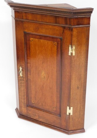 An oak and mahogany hanging corner cabinet, with single drawer, with marquetry shell frieze, a marquetry banding, 865cm high, 61cm wide, 37cm deep.