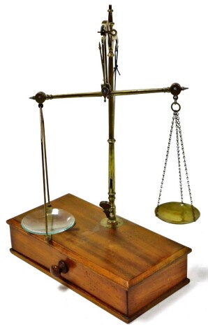 An early 20thC chemists scale, with two brass balance, on a wooden base, 33cm high, 24cm wide, 13cm, deep.