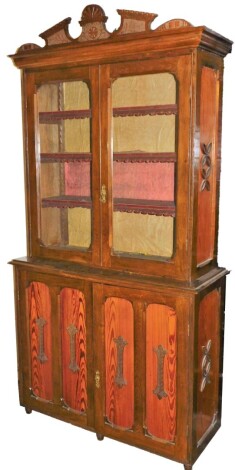 A Victorian pitch pine cabinet bookcase, the top with two glazed doors with leather inset shelves, and a carved pediment, on a cupboard drawer base, 215cm high, 110cm wide, 43cm deep.