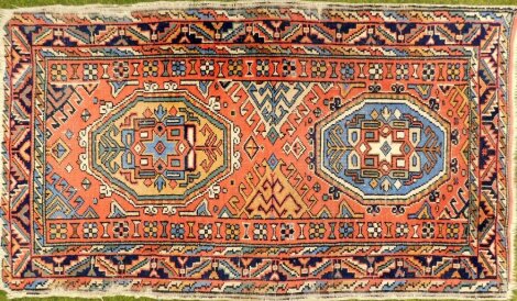 A Middle Eastern rug, on a peach ground, with two central medallion panels, with floral border on tassel ends, 137cm x 79cm.