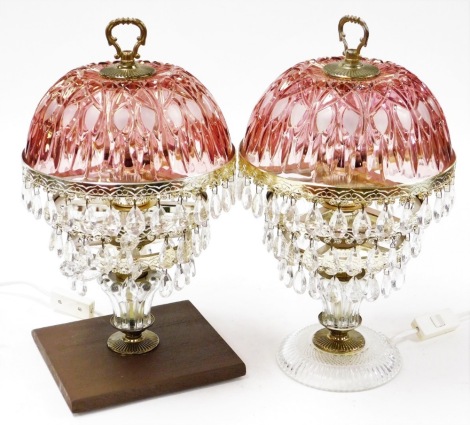 Two similar table lamps, each with cranberry glass shade top and layered tear drop lustres, on varying bases, 37cm high.