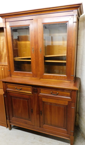 A modern cherry wood bookcase/display cabinet, the cabinet top with two adjustable bookshelves, above two drawers and cupboard enclosed by two doors, on tapered legs, with cornice, 209cm high, 130cm wide, 53cm deep.