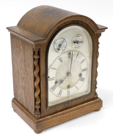 An oak cased mantel clock, with silvered colour dial with chime and silent movement, with barley twist columns, 35cm high, 26cm wide, 17cm deep.