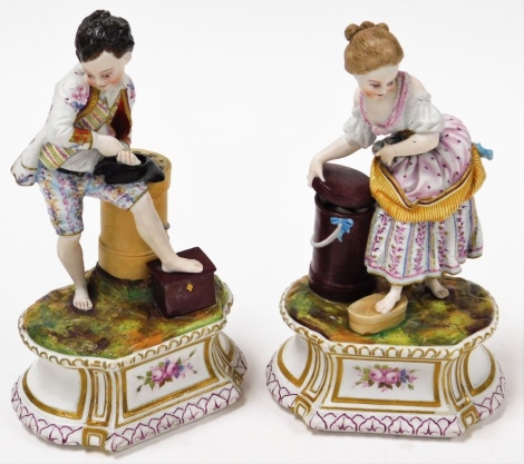 A pair of French gilt bisque figures, depicting boy and girl, with floral scroll detailing to the base, 20cm high.