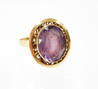 An amethyst set dress ring, the oval amethyst in rub over setting with floral etched raised border and shaped shoulders yellow metal stamped K18, ring size P, 5.7g all in.