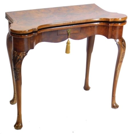 A mid 18thC walnut card table, the figured top with feather banded border and rounded corners, enclosing a baize lined interior, with dished counter or coin wells, above a small frieze drawer on cabriole legs, headed by shell and leaf carving, 74cm high, 