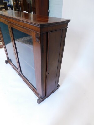 An early 19thC mahogany freestanding library bookcase, the top with a moulded crest above two glazed doors, each flanked by roundel's, the reverse with two panelled doors, and with further side doors to each narrow end, on leaf carved end supports with ca - 2