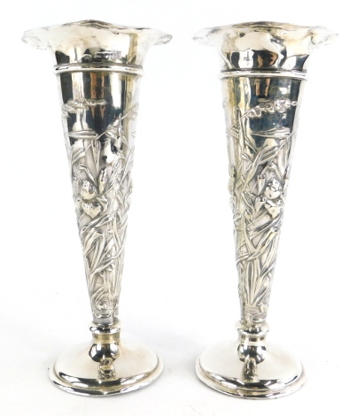 A pair of early 20thC silver vases, by William Comyns and Sons, of tapering trumpet form with a fluted rim, cast with reeds, flowers, etc., on loaded bases, London 1900 and 1901, 20.5cm high. (AF, 2)