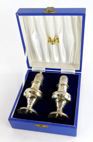 A pair of Elizabeth II silver pepper pots, of baluster form, in fitted box, Birmingham 1980. 5¾oz, 14cm high with finial. (2, AF, one lacking finial)