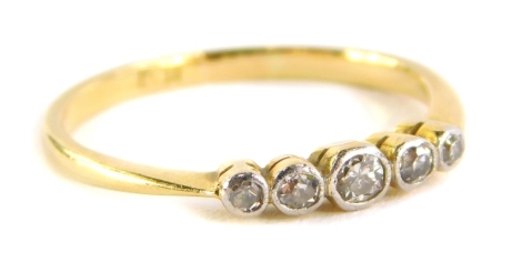 A five stone diamond dress ring, with five tiny diamonds, in rub over platinum setting, on a yellow metal band, marked 18ct, ring size L½, 1.5g all in.