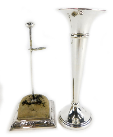 Two items of small silver, to include a silver trumpet shaped vase, of plain form with a loaded base, Birmingham 1928, 15cm high, and a George V hat pin stand, with a cushioned platform raised on a square pedestal base decorated with swags, bows etc., Che