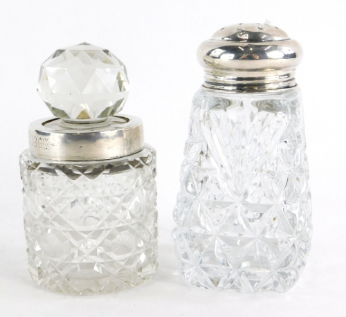 Two cut glass dressing table jars, one with a cut glass stopper and silver collar, engraved with the inscription A. Ekin Oct 9th 1900, Birmingham 1899, 11cm high, the other with a silver topped screw top lid, Birmingham 1938, 12cm high. (2)