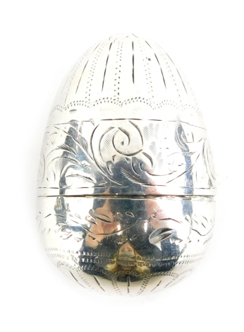 A white metal egg shaped nutmeg grater, decorated with scrolls, leaves and line decoration, 4cm high.