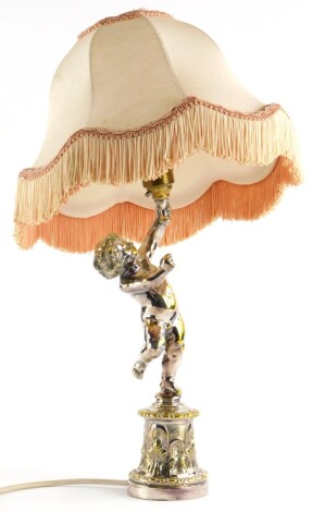 A silver plated brass table lamp, modelled in the form of a putto on a cylindrical base with shade, 42cm high overall.