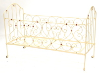 A Victorian folding wrought iron child's bed or cot, with scroll decoration, later painted in pink and red, 138cm wide.