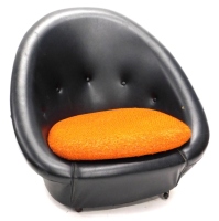 A 1960s retro black leatherette egg shaped chair, with yellow cushion, 86cm wide. The upholstery in this lot does not comply with the 1988 (Fire & Fire Furnishing) Regulations, unless sold to a known exporter or upholsterer it will be cut from the frame b