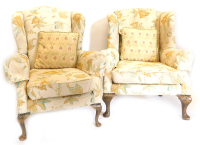 An associated pair of mahogany wingback chairs in George III style, each upholstered in gold and turquoise floral fabric, on cabriole legs with pad feet.