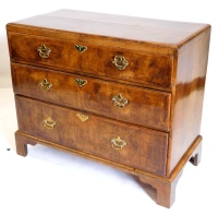 A mid 18thC walnut chest of drawers, the quarter veneered top with a central oval and feather banded border, above three crossbanded drawers with brass handles on bracket feet, adapted, 85cm high, 100cm wide, 50cm deep.