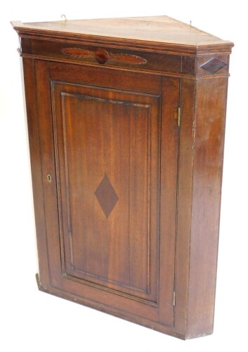 A 19thC oak and mahogany hanging corner cabinet, with a moulded cornice above a panelled door, inlaid with a central lozenge, 94cm high, 78cm wide.