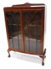 An early to mid 20thC mahogany bowfronted display cabinet, with a raised back above two glazed doors enclosing shelves, on cabriole legs with ball and claw feet, 88cm wide.