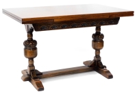 An oak draw leaf extending dining table, in Tudor style, the rectangular top above a carved frieze on leaf carved cup and cover supports, with flat stretcher, 77cm high, the top 81cm x 182cm.