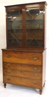 An early 19thC mahogany secretaire bookcase, the top with a moulded corner above two astragal glazed doors, the ebony strung base with a fitted fall front drawer above three further drawers, each with cast brass oval handles and turned feet, the base and 