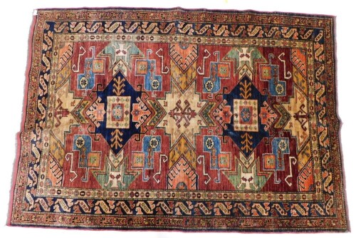 An Afghan Kazak style rug, with a multi coloured design of lozenges, geometric devices, etc., in shades of blue, coral, beige, yellow, etc., with one wide and two narrow borders, 200cm x 141cm.