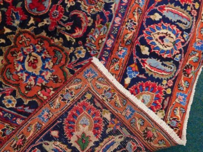 A large Persian Meshed type carpet, with a central medallion, surrounded by an elaborate design to the floral red ground, with blue spandrels, one wide and three narrow borders, 373cm x 280cm. - 3