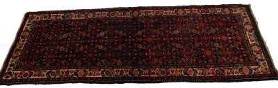 A Persian narrow rug, with an all over design, on a deep navy ground, one wide, two narrow borders, 195cm x 110cm.