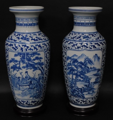 A pair of Chinese porcelain baluster vases, having blue and white landscape decoration, 54cm high with attached base.