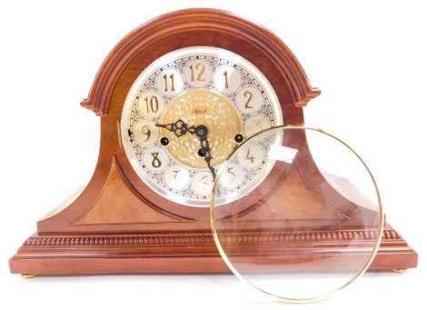 A Franz Hermle mahogany cased mantle clock, circular silvered dial bearing Arabic numerals with central foliate fret work, eight day movement, with Westminster chimes, the case of Napoleon hat form, with key, 29cm high, 46cm wide. (AF)