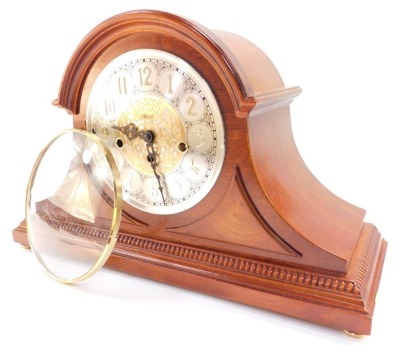 A Franz Hermle mahogany cased mantle clock, circular silvered dial bearing Arabic numerals with central foliate fret work, eight day movement, with Westminster chimes, the case of Napoleon hat form, with key, 29cm high, 46cm wide. (AF) - 2