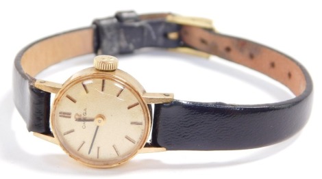 An Omega 9ct gold cased lady's wristwatch, circular champagne dials with gold batons, on a leather strap.