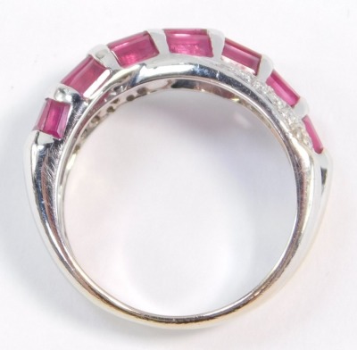 A ruby and diamond crossover ring, set with twenty one baguette cut rubies in white metal, stamped 585, size M, 4.7g. - 3