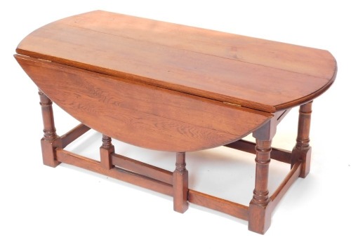 An oak drop leaf coffee table, with an oval top on turned supports, 115cm wide.