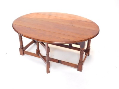 An oak drop leaf coffee table, with an oval top on turned supports, 115cm wide. - 2