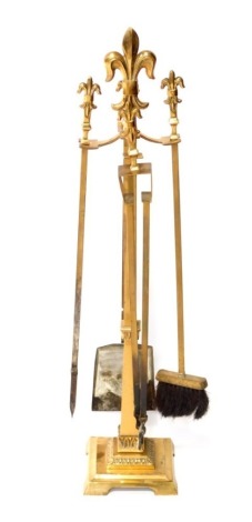 A set of 20thC brass fire irons, each on a stand, and with fleur de lys finial, on a square base, with bracket feet, stand 77cm high.