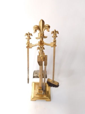 A set of 20thC brass fire irons, each on a stand, and with fleur de lys finial, on a square base, with bracket feet, stand 77cm high. - 2