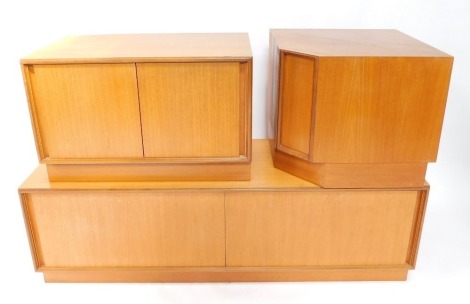 An E Gomme Ltd 1970's teak low corner unit, in three sections, with sliding doors, on a plinth, each 49cm high.