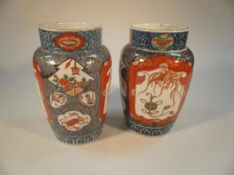A pair of Chinese Imari ovoid vases painted with iron red panels of mythical