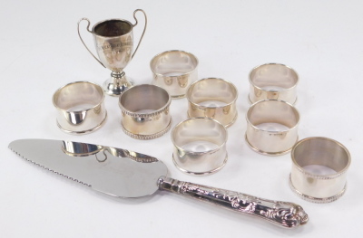 A set of six Elizabeth II silver napkin rings, by Francis Howard Ltd, Birmingham 1962, with a pair of additional napkin rings, a commemorative cup and a silver handled cake slice, 5.32oz all in. - 2