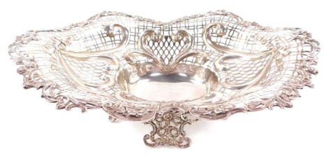 A Victorian silver centrepiece bowl, having elaborate scrolled and floriate rim, surrounding a multi patterned pierced lattice work design, with heart shaped moulded scrolls, surmounted by ribbon bows, with centre oval reservoir, raised upon a quadriparti