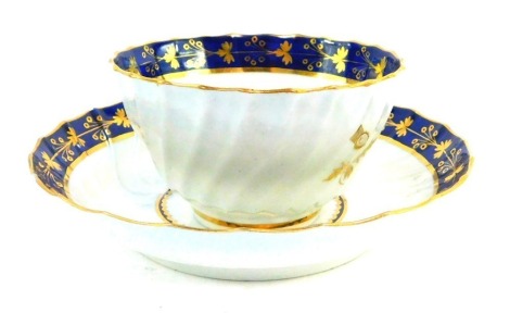 A First Period Worcester porcelain tea bowl and matching saucer, having blue scale rim with gilt floriate decoration, with a central blue and gilt ring encompassing a thistle, with small blue crescent mark to both, c1793, saucer 13.5cm diameter.